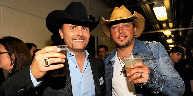 Jason Aldean and John Rich wear cowboy hats and toast backstage