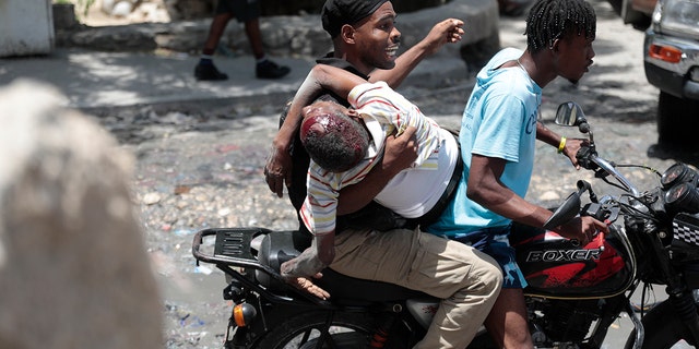 Kenyan police officer holding injured resident