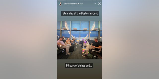 Kristen Bell and her group of friends and children at the airport in Boston sitting on seats smiling for a picture