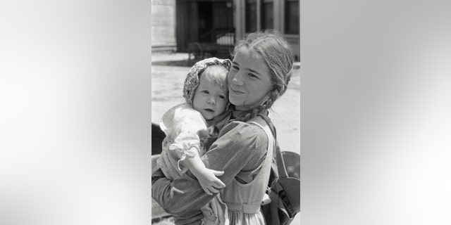 Melissa Gilbert in costume holding onto either Wendi Lee or her twin sister on set