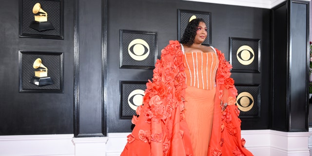 Lizzo in a orange dress and cape at the Grammy Awards