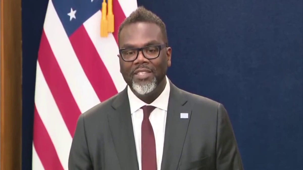 Mayor Brandon Johnson speaking at a press conference with an American flag behind him