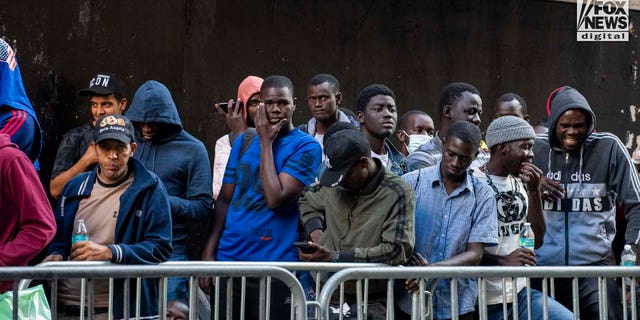Migrants await registration outside of the Roosevelt Hotel