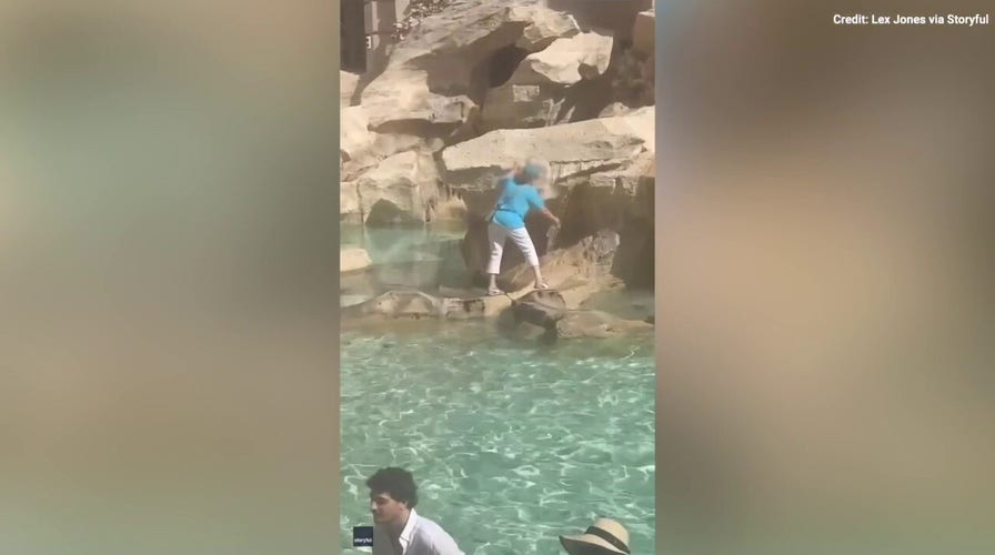 Woman wades through historic fountain to fill water bottle 