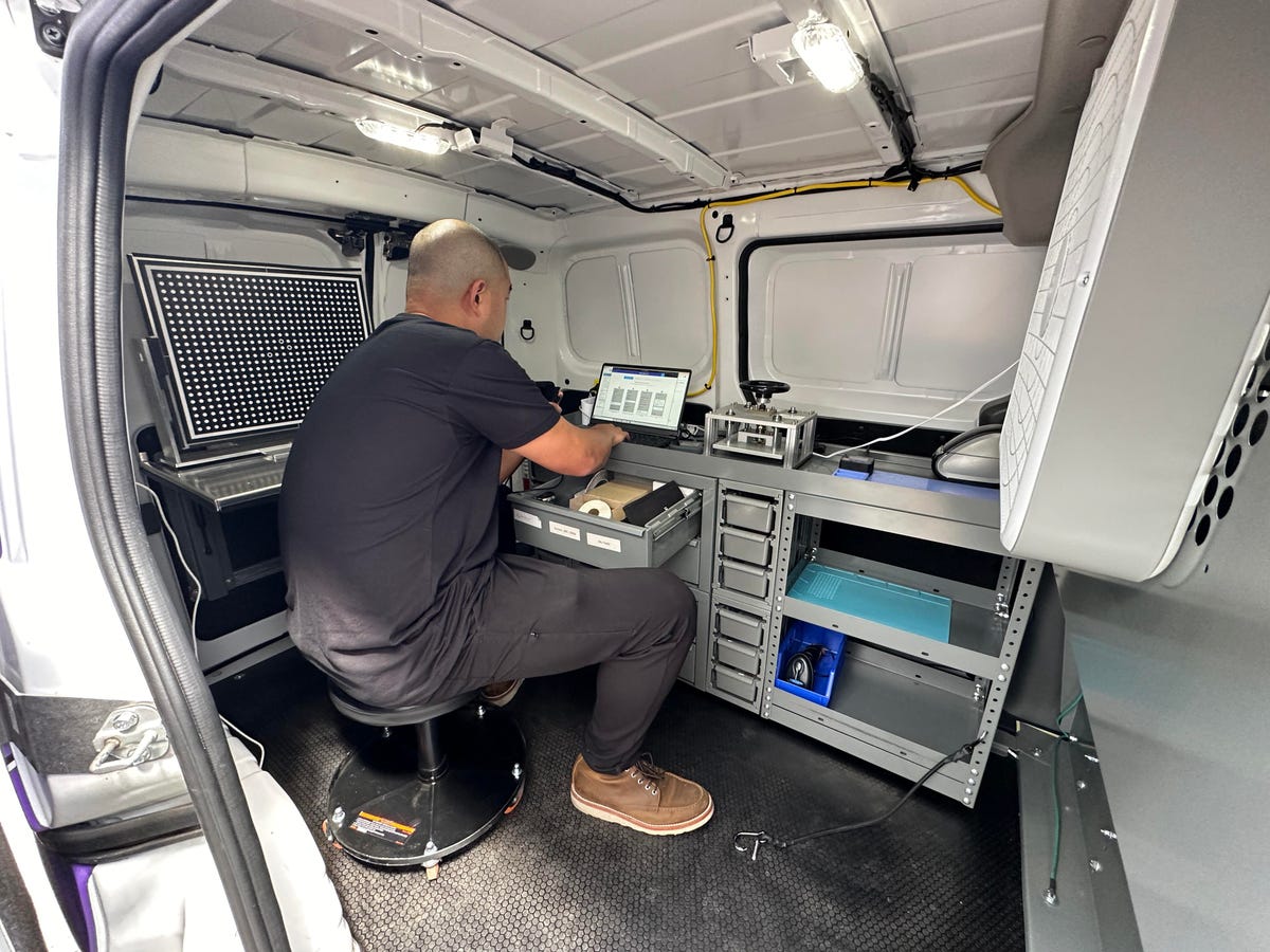 Man sitting in van repairing a phone