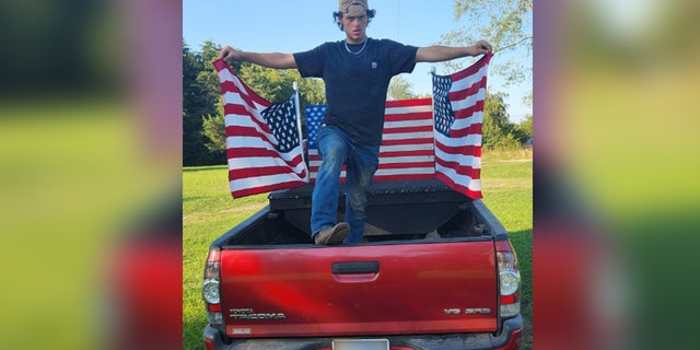 Christopher Hartless standing on red truck with American flags