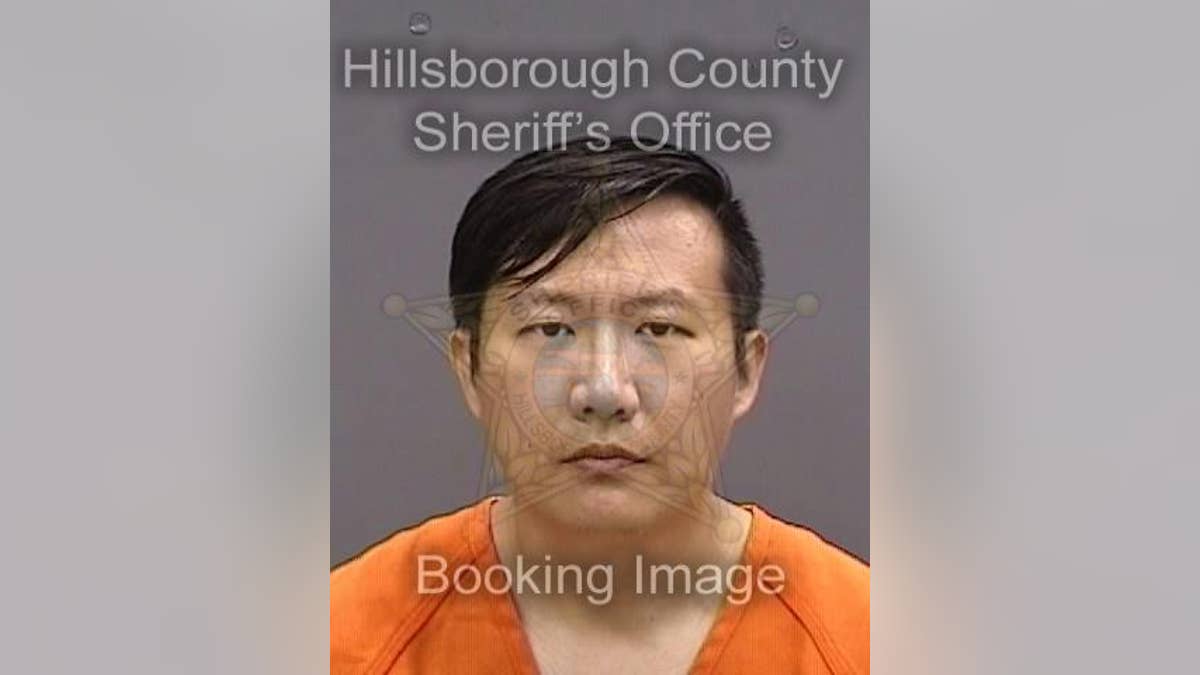 Xumong Li stares stonefaced wearing an orange jumpsuit