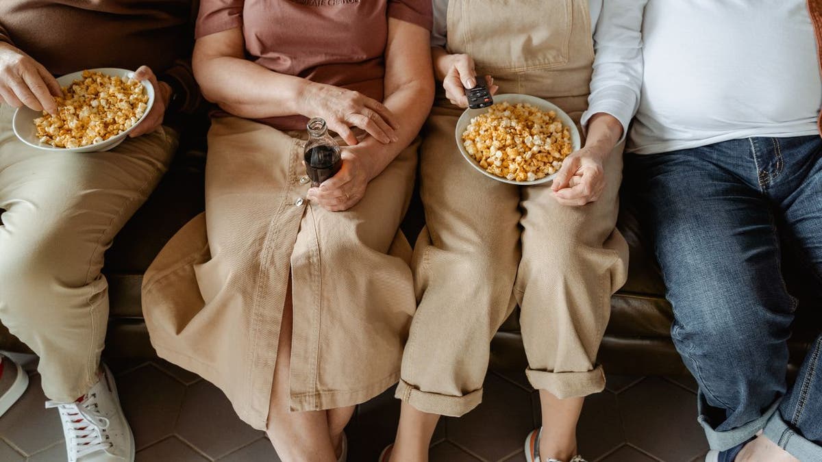 Family sitting down and watching TV.