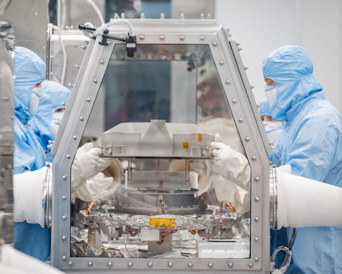 Lockheed Martin Recovery Specialists Levi Hanish and Michael Kaye remove the lid of the sample return canister.