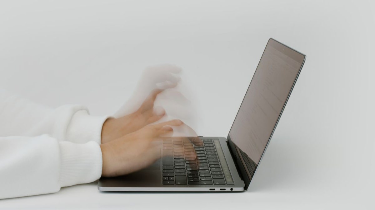 Person typing on their laptop.