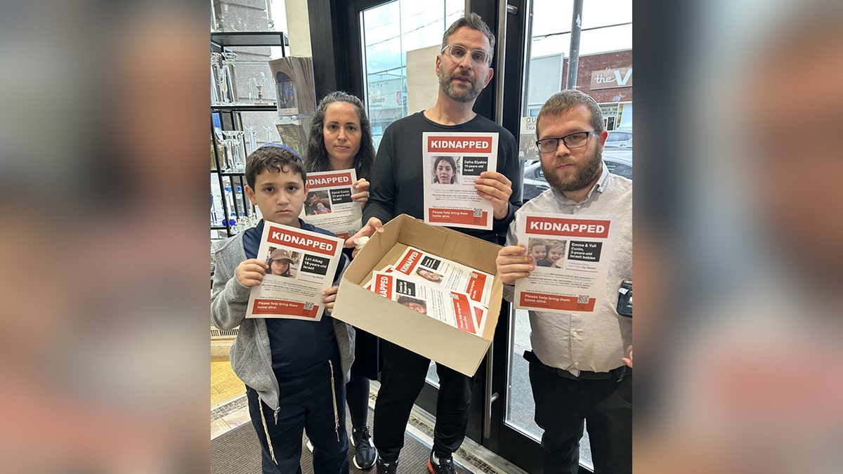 Family holding up posters for missing individuals