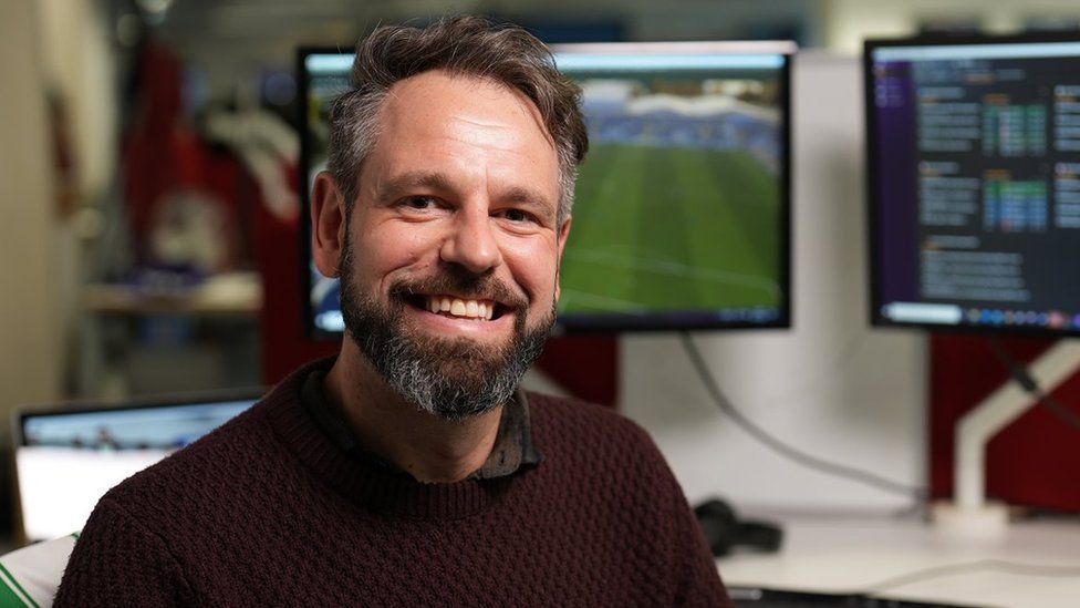 Nic Madden sitting in front of screens showing the Football Manager game