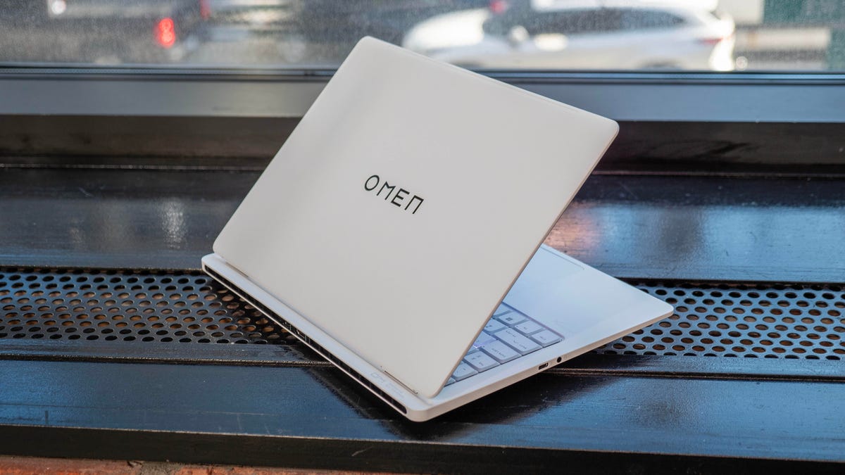 HP Omen Transcend 14 open facing rear right sitting on a black window ledge and a window behind it.