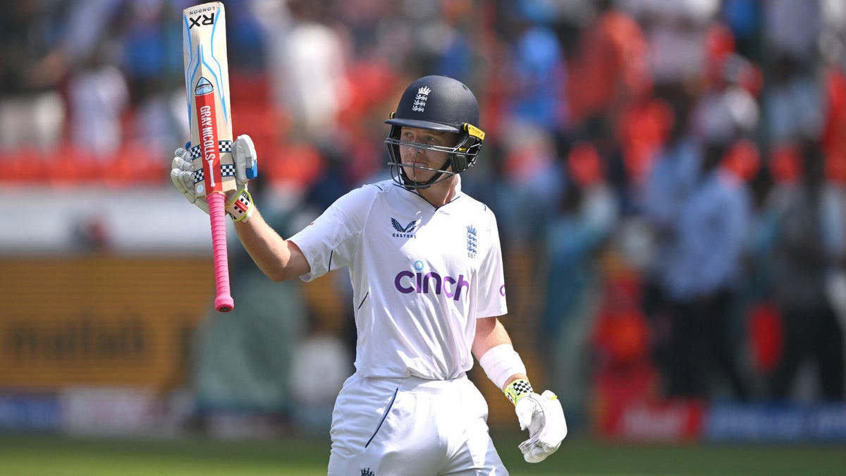 England batsman Ollie Pope celebrating holding aloft a bat with his right hand.