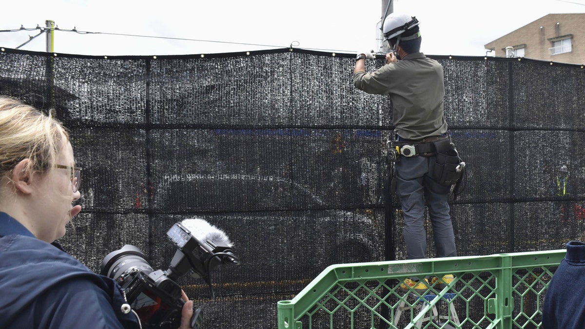 A worker sets up a huge black screen on a stretch of sidewalk at Fujikawaguchiko town, Yamanashi prefecture, central Japan