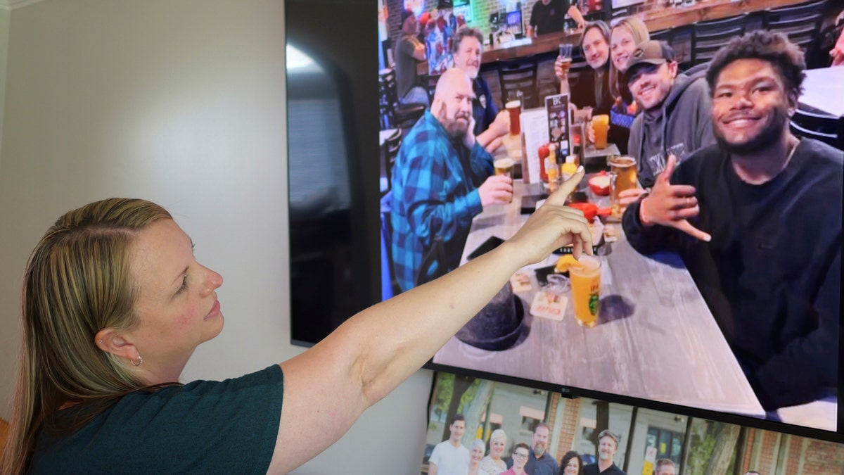 Rebecca Higbee the mother of Tyler Thompson, points to her son and his friend Marcel in a picture from his 21st birthday with his family.
