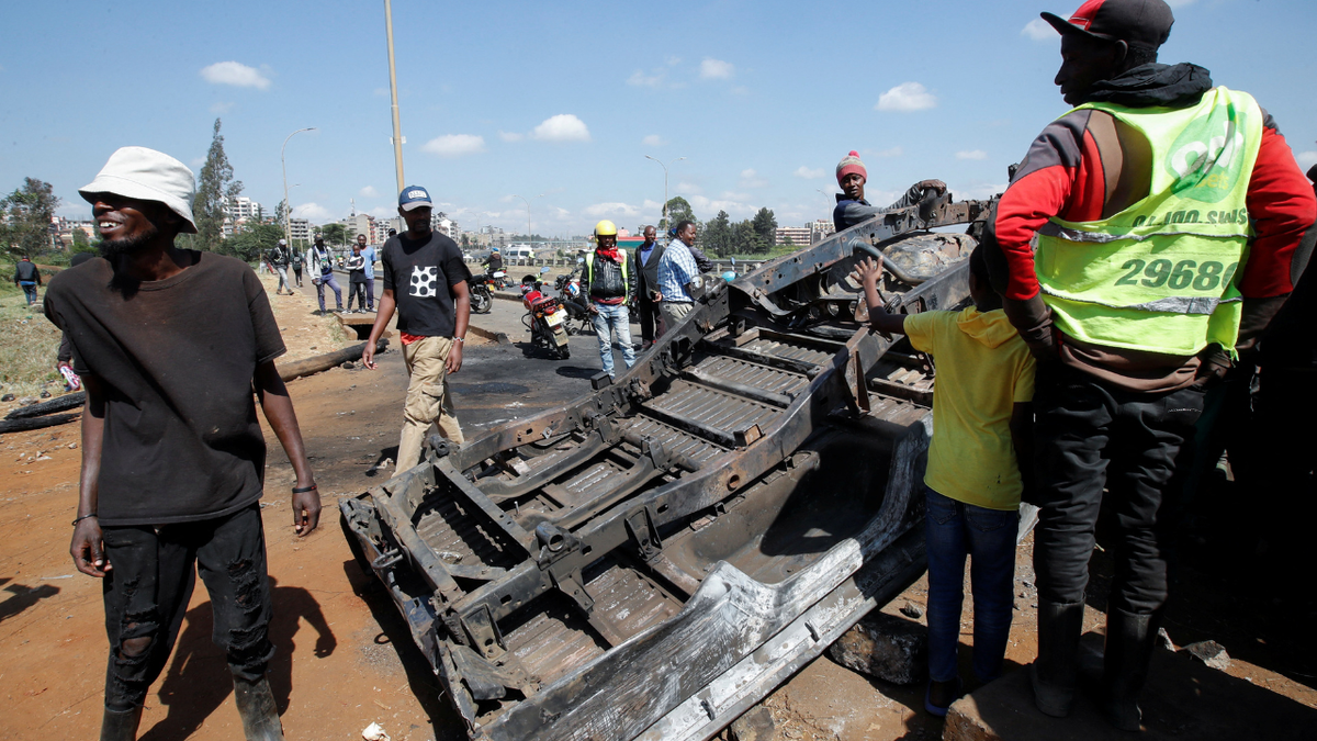 People stand next to a burned police vehicle