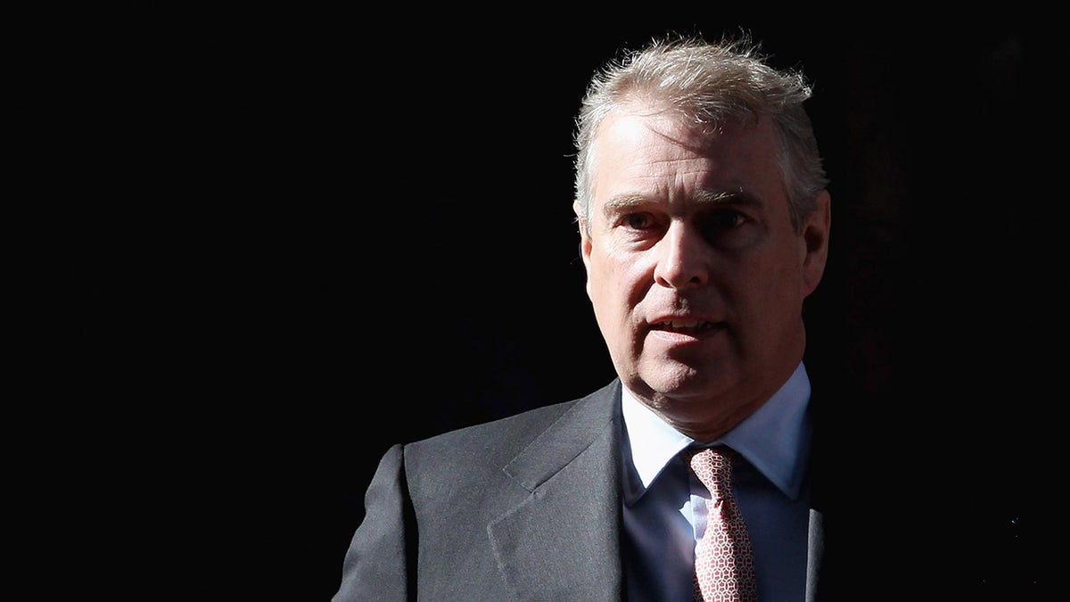 Prince Andrew in a grey suit against a black background looking concerned.