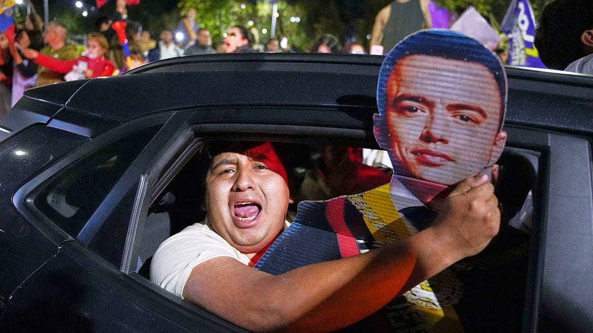 Noboa supporter holds a placard of his face out of a car window