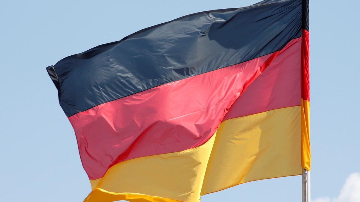 The German national flag is seen on a sunny day surrounded by some clouds at the Chancellery in Berlin, Germany, April 29, 2016. REUTERS/Fabrizio Bensch - RTX2C625