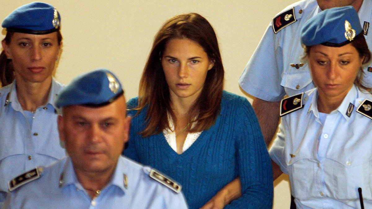 Amanda Knox being escorted by police.