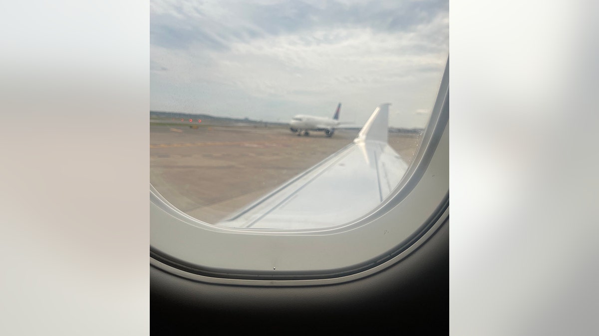 view through airplane window of second plane on tarmac
