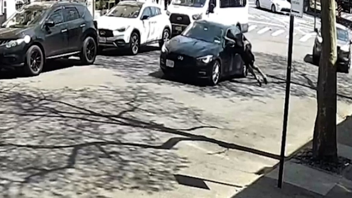 man hanging onto driver's window as car drives away