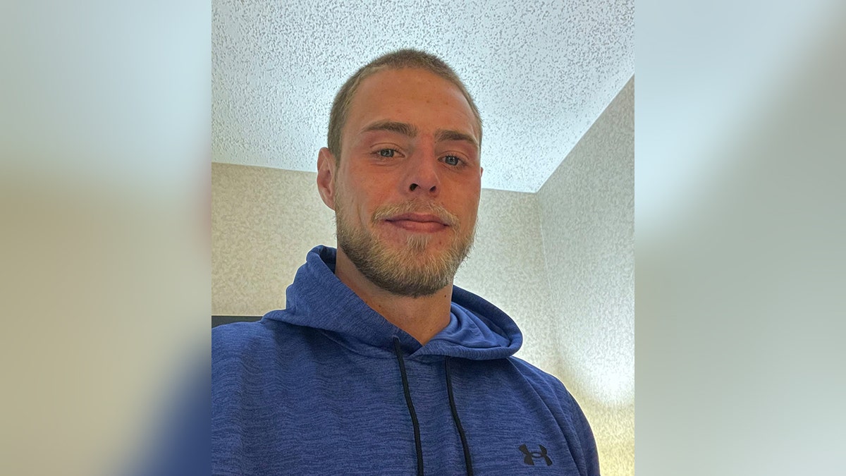 Jacob Couch smiles with blonde beard wearing a blue sweatshirt