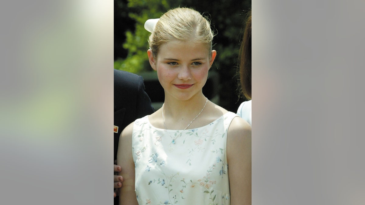 A young Elizabeth Smart wearing a sleeveless white floral dress smiling.