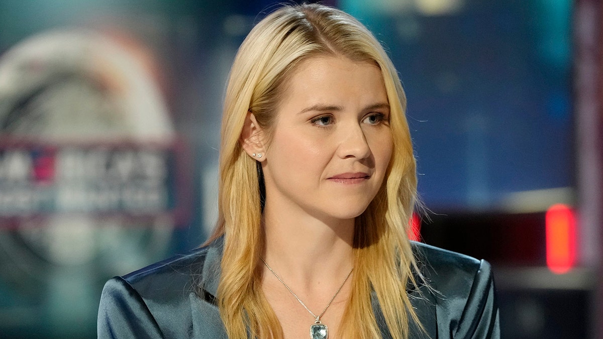A close-up of Elizabeth Smart looking serious in a blue blazer.