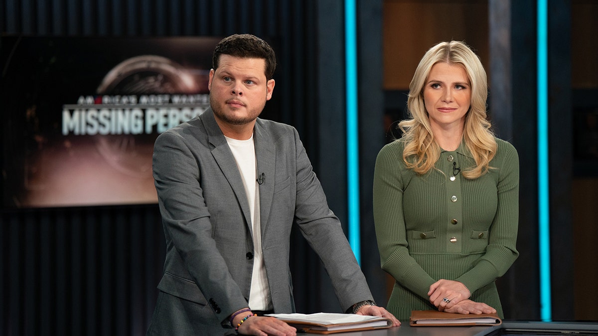 Elizabeth Smart wearing a green sweater listening intently next to a man in a grey blazer and white shirt.