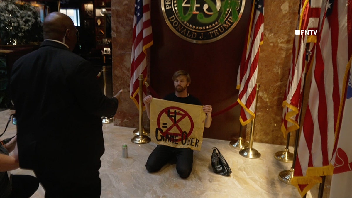 A climate protester kneeling in Trump Tower