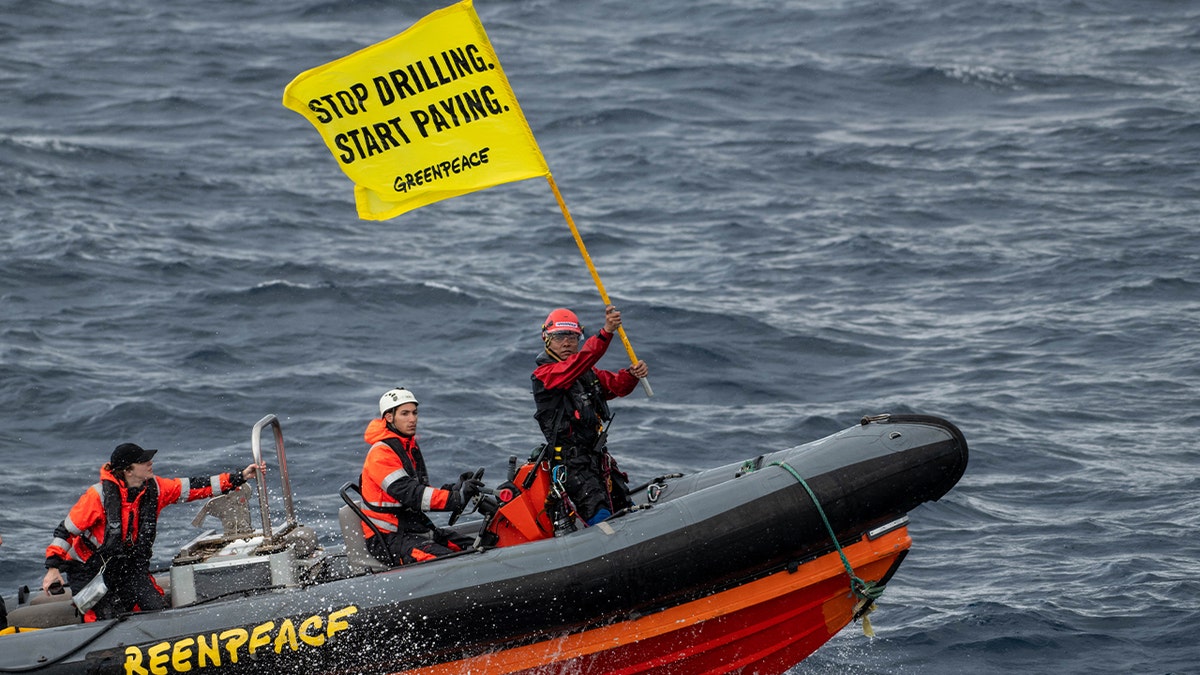 Greenpeace activist Yeb Saño from the Philippines holds aloft a flag on a small boat after attempting to board a Shell oil platform being transported by the White Marlin ship on Jan. 31, 2023 in the Atlantic Ocean north of Gran Canaria, Spain.