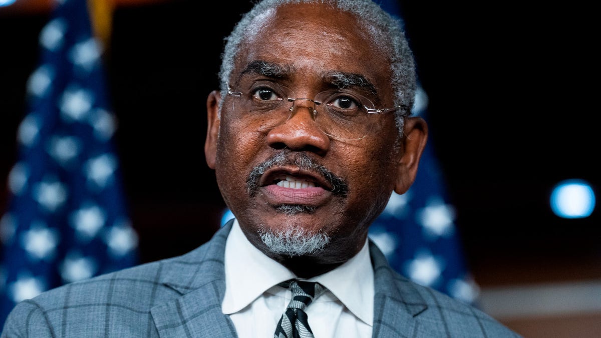 Gregory Meeks looking at camera with an American flag in background