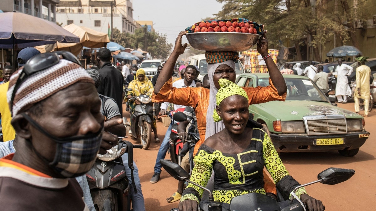 A woman carries strawberries through the streets of Ouagadougou on January 28, 2022. - Burkina Faso, the scene of a military coup on Monday, was suspended from the Community of West African States (ECOWAS) on Friday, following a virtual summit of the organization whose heads of state will meet again on February 3 in Accra to reassess the situation in this country.