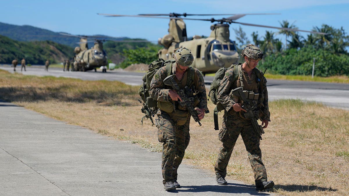 servicemen on tarmac, helicopters in background