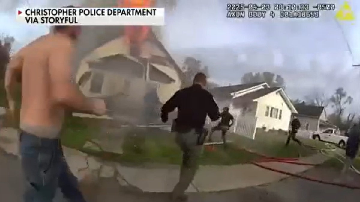 First-responders can be seen running toward the aftermath of a home explosion to rescue a trapped firefighter.