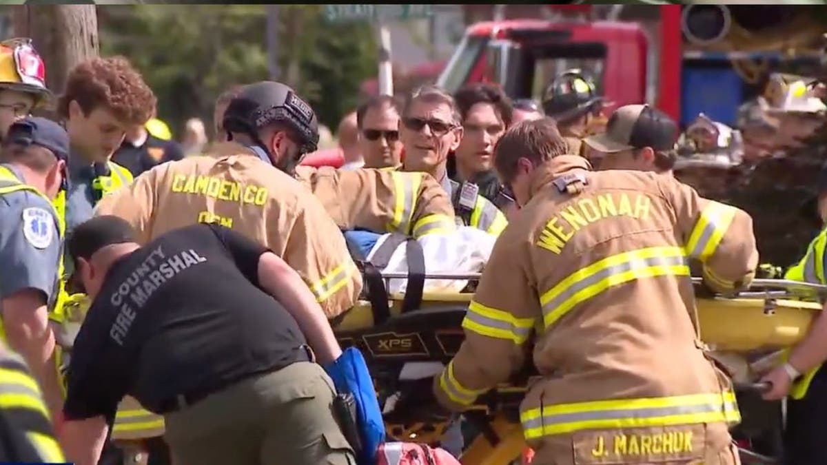 The truck driver being taken to away in a gurney.