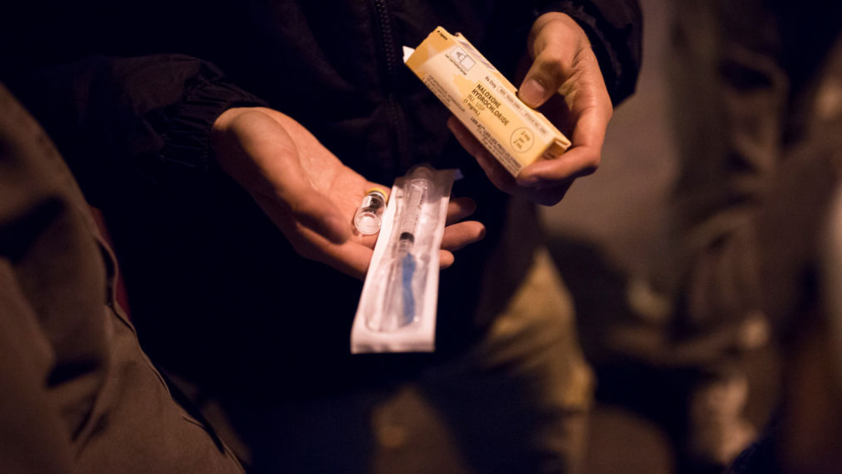 A man hands out a syringe on the streets of Maine.