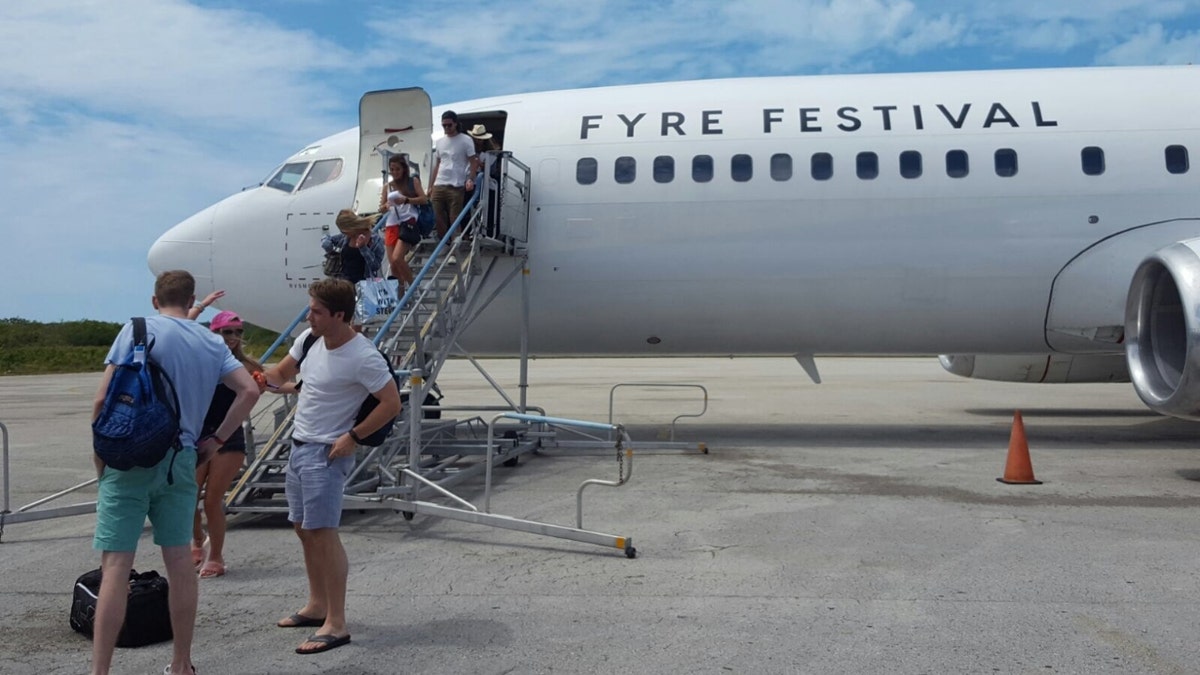 Fyre Festival attendees de-board a small plane that reads "Fyre Festival" on its side in the Bahamas in 2017.