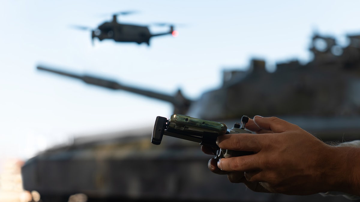 A drone flies by a military tank