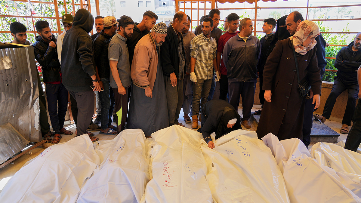 Mourners walk by bodies