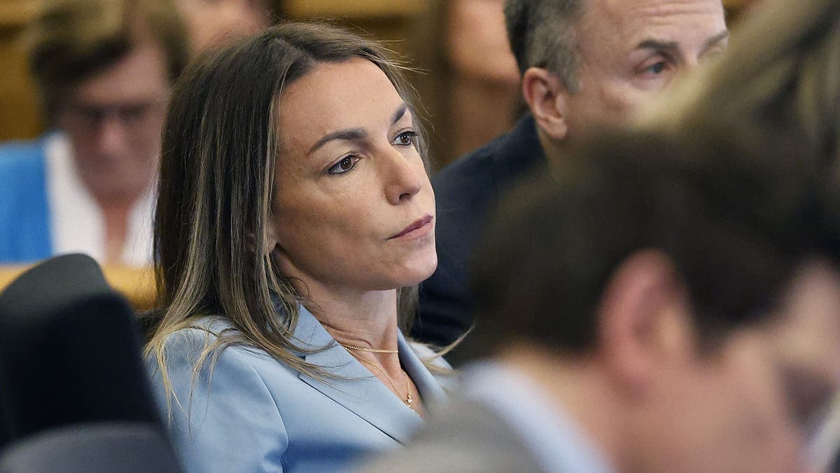 Karen Read leans back at the defense table wearing a light blue blazer