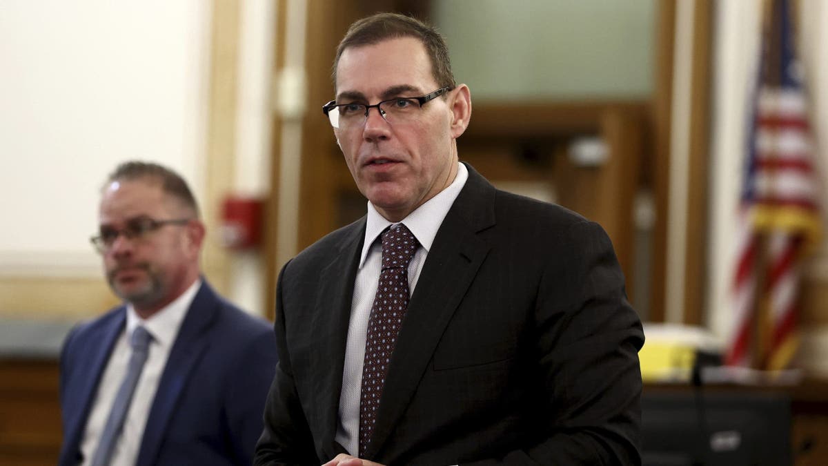 Special prosecutor Hank Brennan speaks in court, wearing a dark suit, dark tie and white shirt. he has short hair and is wearing glasses.