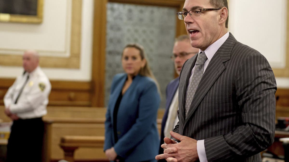 Prosecutor Hank Brennan introduces himself to jury members wearing a dark pinstriped suit and glasses