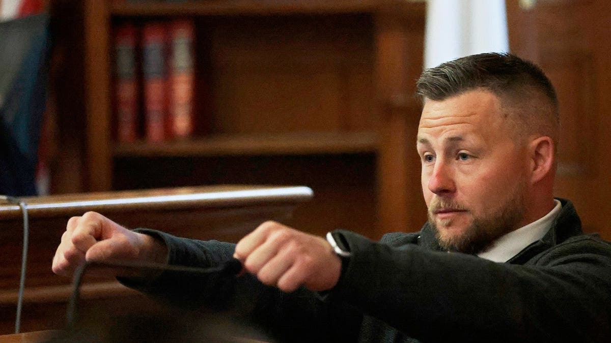 Ryan Nagel gestures as if he is holding a steering wheel from the witness stand