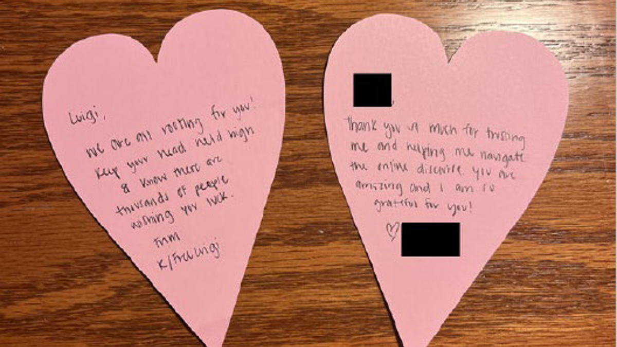 Two pink, heart-shaped letters on a wooden table