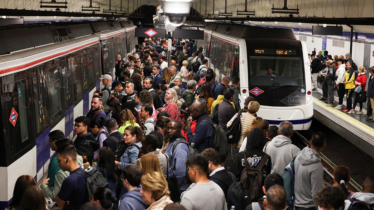 People stand on train platform in Madrid