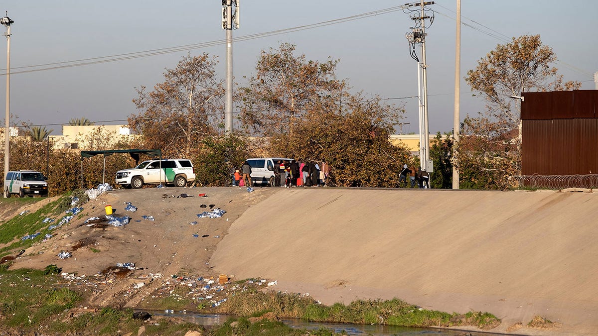 Migrants stand near the border