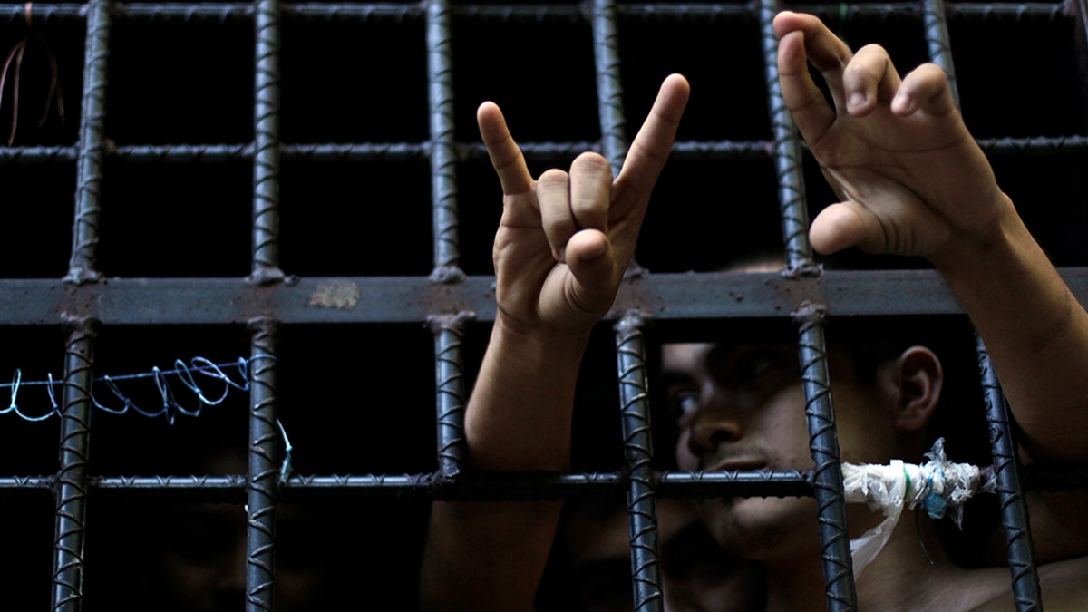 A man arrested this week for being a member of the MS-13 Mara Salvatrucha street gang among other crimes, flashes his gang's hand sign from inside a jail cell at a police station in San Salvador October 12, 2012. The U.S. on Thursday imposed financial penalties on violent Latin American street gang MS-13, which has thousands of members operating in the U.S. and has been accused of human trafficking, kidnapping, murder, rape and other criminal activities. MS-13, whose U.S. members are mostly first-generation Salvadorean-Americans or Salvadorean nationals, was added to the Obama administration's list of transnational criminal organizations - a label designed to cripple a criminal group's finances. REUTERS/Ulises Rodriguez (El SALVADOR - Tags: CIVIL UNREST CRIME LAW) - GM2E8AD0RWT01